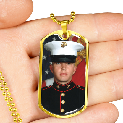 Goldfarbener Dog-Tag-Fotoanhänger in der Hand als Größenvergleich
